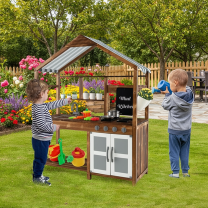 Two children playing with a wooden play kitchen set in a garden.
