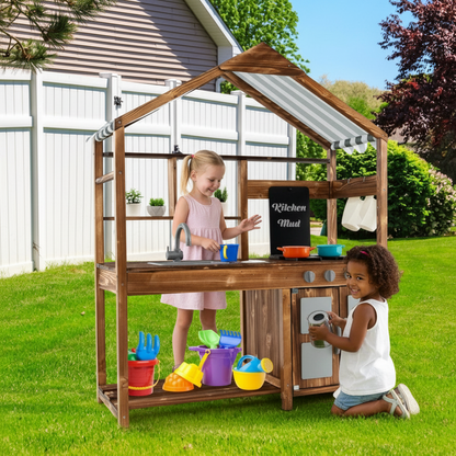 Two children playing with a wooden play kitchen set outdoors on a sunny day.