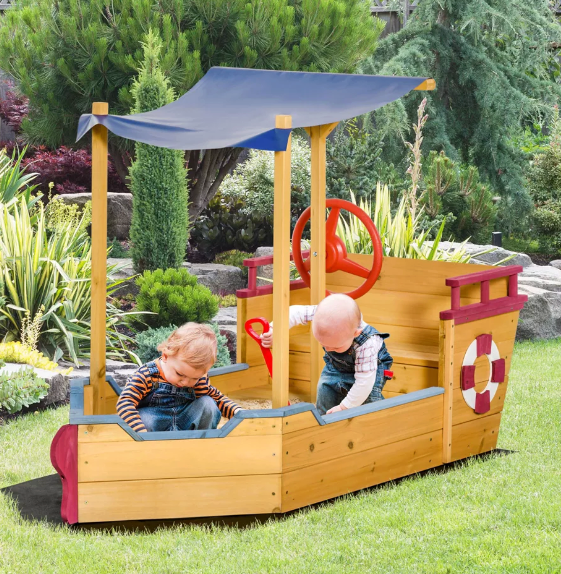 Children playing on a wooden pirate ship playset in a garden.