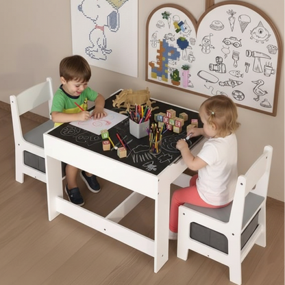 Two children sitting at a white children's table with a blackboard surface, drawing and playing.