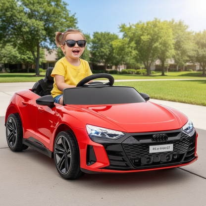 Child in a red toy Audi car with sunglasses on a suburban street.