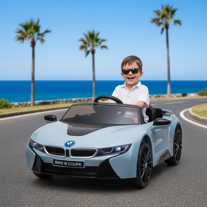 Child driving a toy BMW i8 Coupe on a road with palm trees and ocean in the background